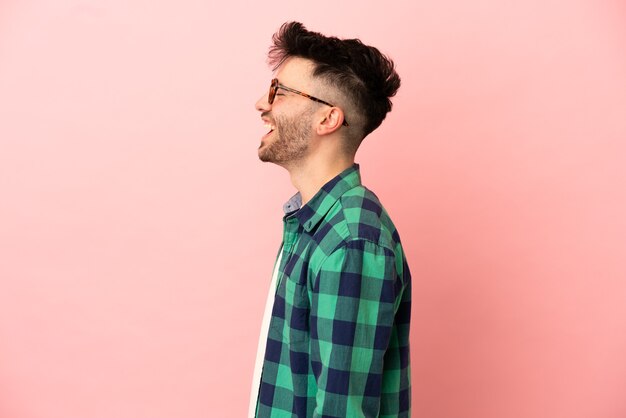 Jonge blanke man geïsoleerd op roze achtergrond lachen in zijpositie
