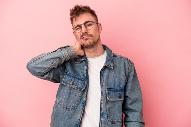 Jonge blanke man geïsoleerd op roze achtergrond met nekpijn als gevolg van stress, masseren en aanraken met de hand.