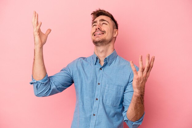 Jonge blanke man geïsoleerd op roze achtergrond schreeuwen naar de hemel, opzoeken, gefrustreerd.