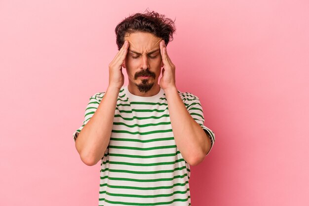 Foto jonge blanke man geïsoleerd op roze achtergrond tempels aan te raken en hoofdpijn te hebben.