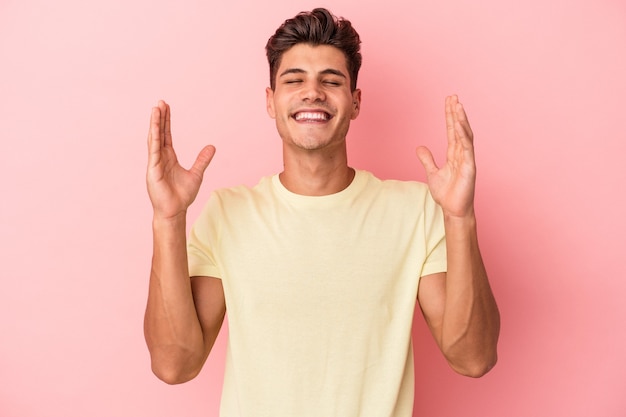 Jonge blanke man geïsoleerd op roze achtergrond vrolijk veel lachen. Geluk concept.