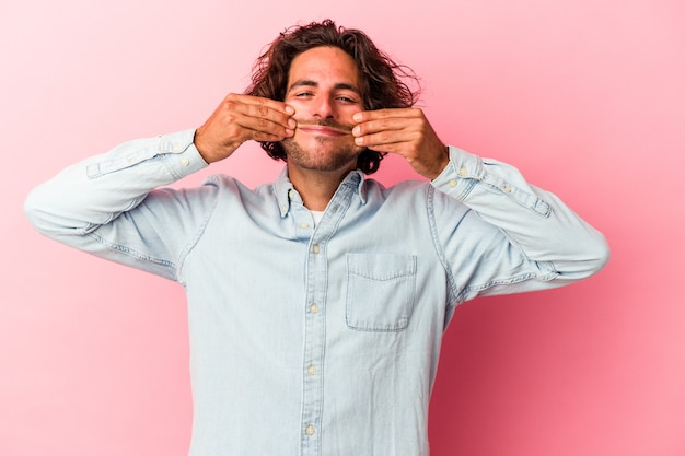 Jonge blanke man geïsoleerd op roze bakcground twijfelen tussen twee opties.