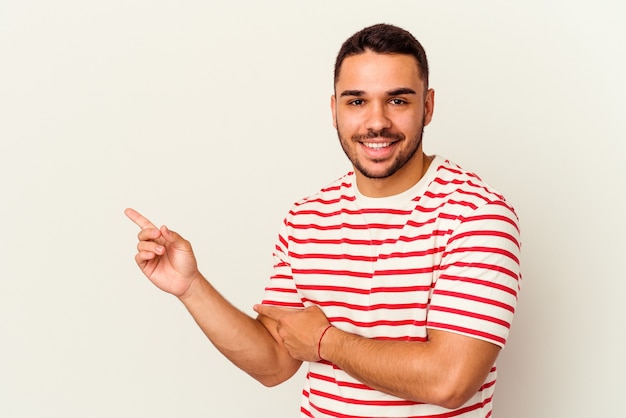 Jonge blanke man geïsoleerd op wit glimlachend vrolijk wijzend met wijsvinger weg.