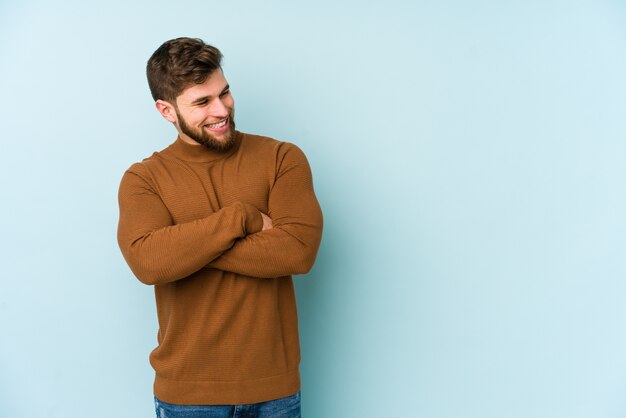 Jonge blanke man glimlachend zelfverzekerd met gekruiste armen.