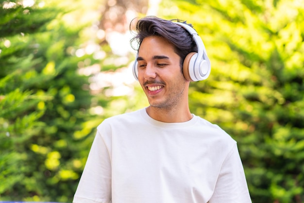 Jonge blanke man in een park die muziek luistert