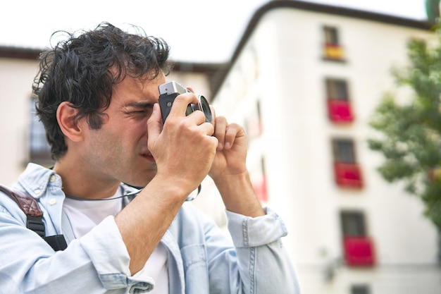 Jonge blanke man legt dierbare herinneringen vast met zijn vintage camera tijdens een heerlijke vakantie