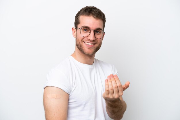 Jonge blanke man met band aids geïsoleerd op een witte achtergrond uitnodigend om met de hand te komen Blij dat je kwam