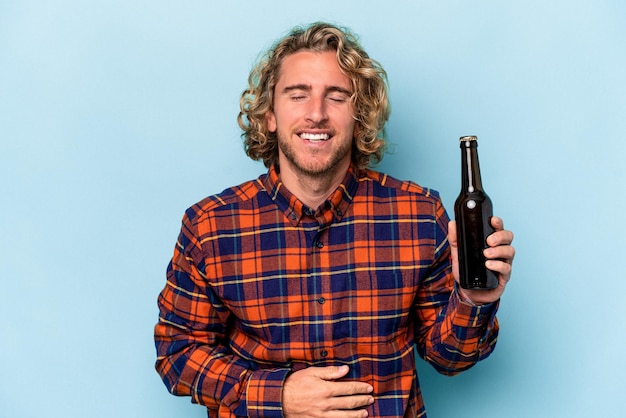 Jonge blanke man met bier geïsoleerd op een witte achtergrond lachen en plezier hebben.