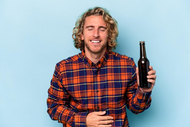 Foto jonge blanke man met bier geïsoleerd op een witte achtergrond lachen en plezier hebben.