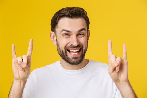 Jonge blanke man met casual t-shirt over geel geïsoleerd schreeuwen met gekke expressie doen rock-symbool met handen omhoog