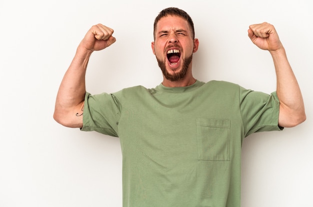 Jonge blanke man met diasteem geïsoleerd op een witte achtergrond die vuist opheft na een overwinning, winnaar concept.