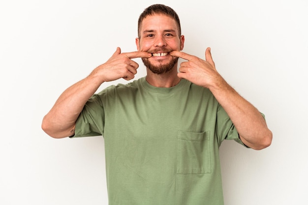 Jonge blanke man met diasteem geïsoleerd op een witte achtergrond glimlacht, wijzende vingers naar de mond.