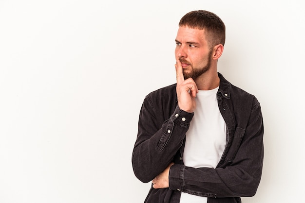 Jonge blanke man met diasteem geïsoleerd op een witte achtergrond op zoek zijwaarts met twijfelachtige en sceptische uitdrukking.