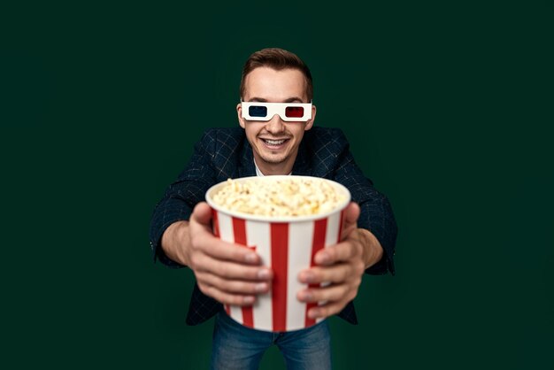 Jonge blanke man met een 3D-bril die popcorn eet.