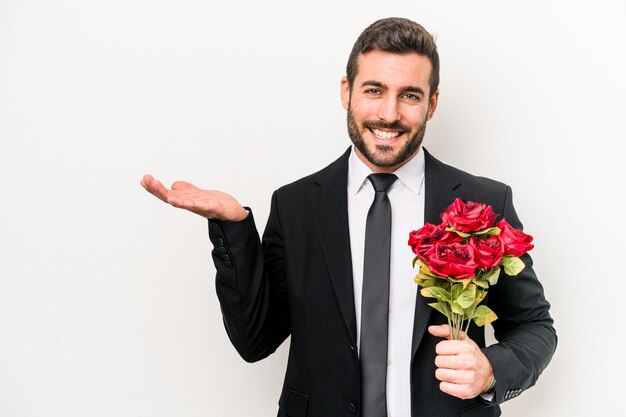 Jonge blanke man met een boeket bloemen geïsoleerd op een witte achtergrond met een kopie ruimte op een palm en met een andere hand op de taille