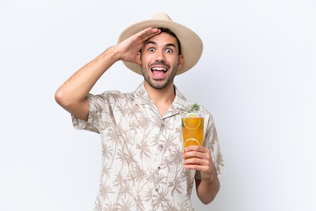 Jonge blanke man met een cocktail geïsoleerd op een witte achtergrond met verrassingsuitdrukking