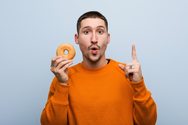 Jonge blanke man met een donut met een geweldig idee, concept van creativiteit.
