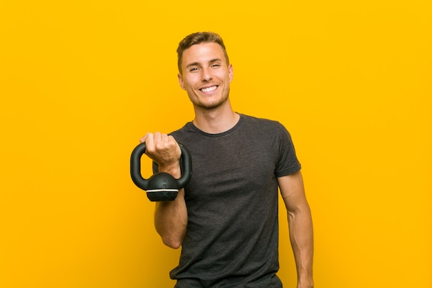 Jonge blanke man met een halter blij, glimlachend en vrolijk.