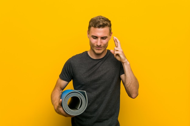 Jonge blanke man met een mat kruising vingers voor het hebben van geluk