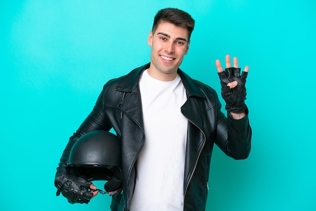 Jonge blanke man met een motorhelm geïsoleerd op blauwe achtergrond gelukkig en vier tellen met vingers
