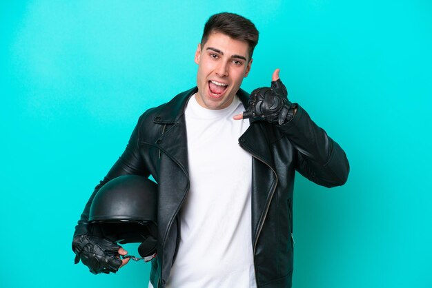 Jonge blanke man met een motorhelm geïsoleerd op blauwe achtergrond telefoon gebaar maken Bel me terug teken