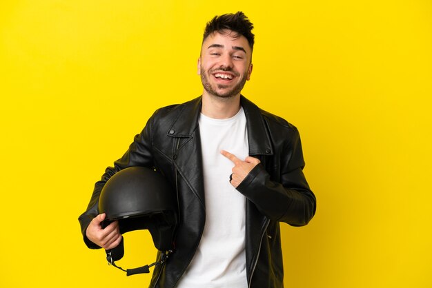 Jonge blanke man met een motorhelm geïsoleerd op een gele achtergrond met verrassende gezichtsuitdrukking