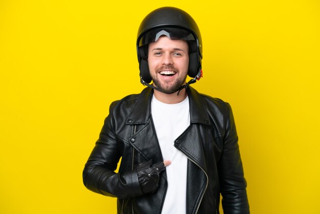 Jonge blanke man met een motorhelm geïsoleerd op een gele achtergrond met verrassende gezichtsuitdrukking