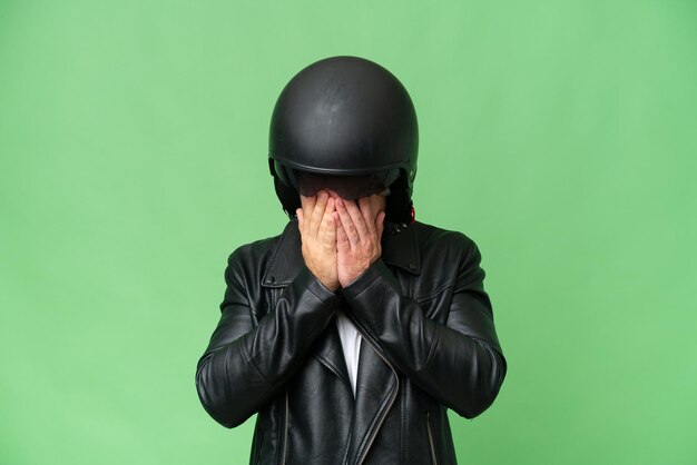 Jonge blanke man met een motorhelm geïsoleerd op groene chroma achtergrond met vermoeide en zieke uitdrukking