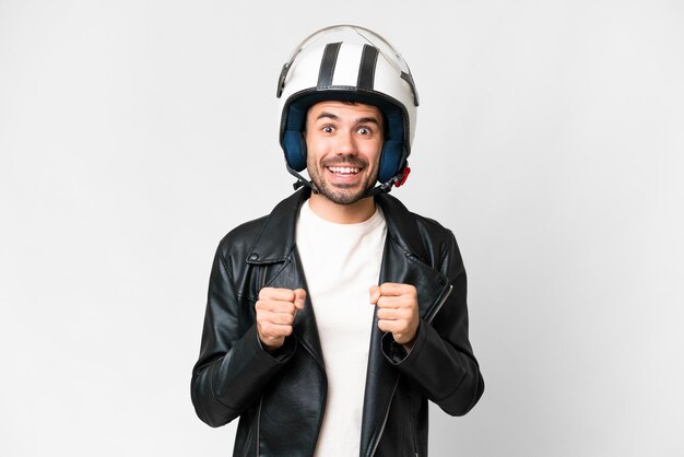 Jonge blanke man met een motorhelm op een geïsoleerde witte achtergrond die een overwinning viert in de positie van de winnaar