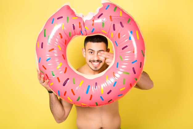 Jonge blanke man met een opblaasbare donut geïsoleerd op gele achtergrond