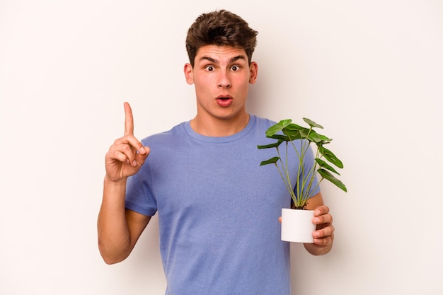 Jonge blanke man met een plant geïsoleerd op een witte achtergrond met een geweldig idee concept van creativiteit