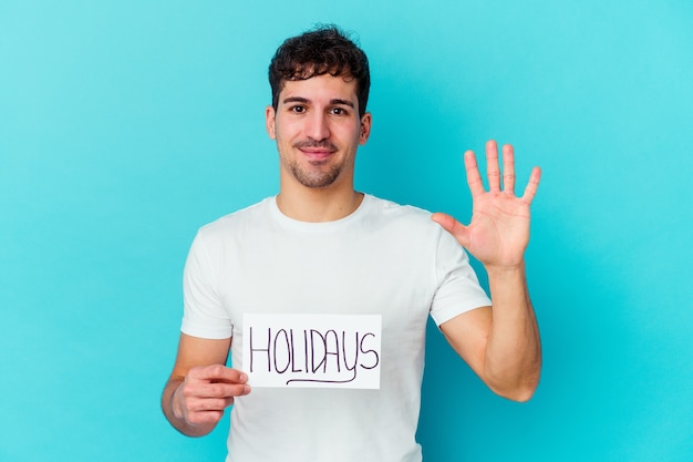 Foto jonge blanke man met een vakantie aanplakbiljet geïsoleerd glimlachen