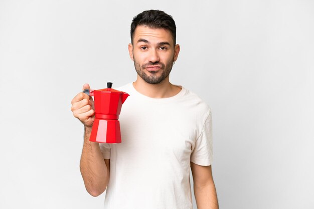 Jonge blanke man met koffiepot over geïsoleerde witte achtergrond met droevige uitdrukking