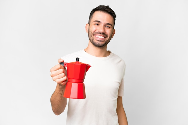 Jonge blanke man met koffiepot over geïsoleerde witte achtergrond met gelukkige uitdrukking