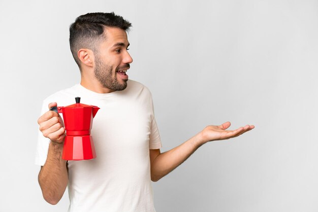 Jonge blanke man met koffiepot over geïsoleerde witte achtergrond met verrassende gezichtsuitdrukking