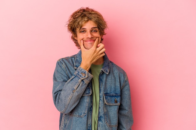 Jonge blanke man met make-up geïsoleerd op roze achtergrond twijfelen tussen twee opties.