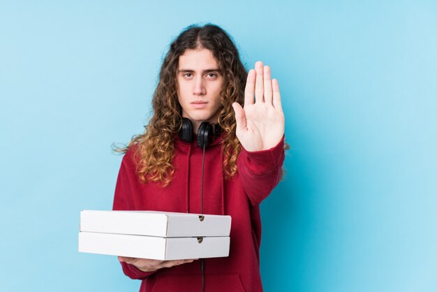 Jonge blanke man met pizza's geïsoleerd staan met uitgestrekte hand met stopbord, waardoor u.