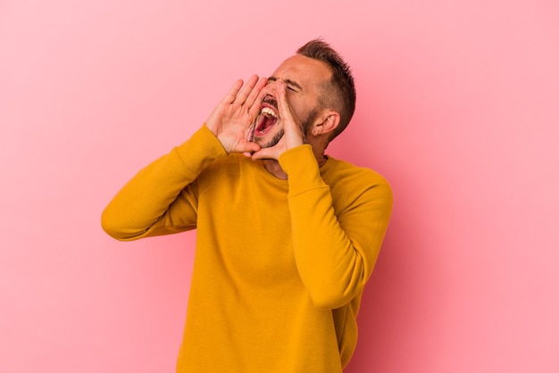 Jonge blanke man met tatoeages geïsoleerd op roze achtergrond opgewonden schreeuwen naar voren.