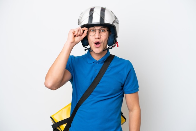 Jonge blanke man met thermische rugzak geïsoleerd op een witte achtergrond met een bril en verrast