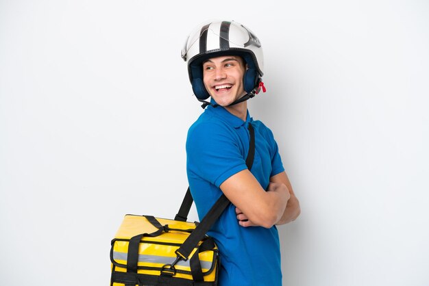 Jonge blanke man met thermische rugzak geïsoleerd op een witte achtergrond met gekruiste armen en happy