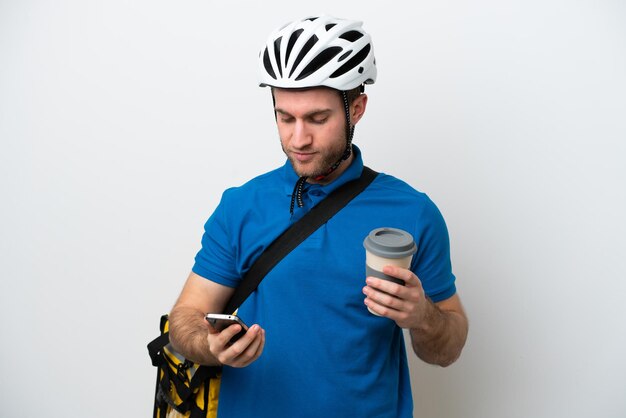 Jonge blanke man met thermische rugzak geïsoleerd op een witte achtergrond met koffie om mee te nemen en een mobiel