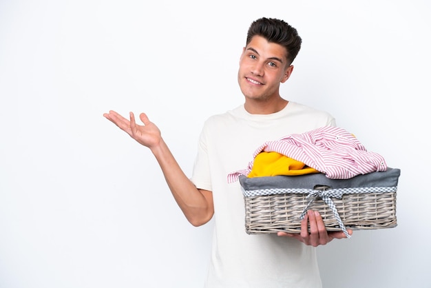 Jonge blanke man met wasmand geïsoleerd op een witte achtergrond die zijn handen naar de zijkant uitstrekt om uit te nodigen om te komen