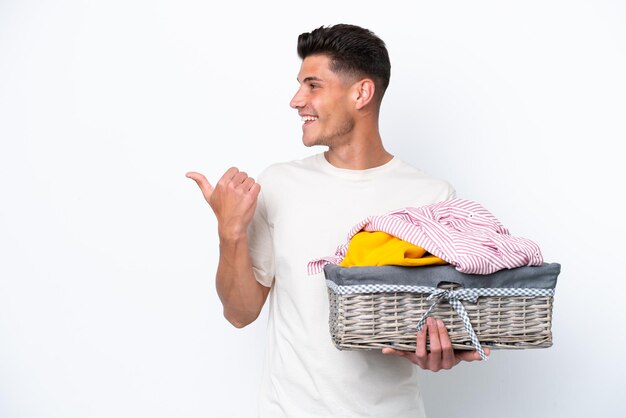 Jonge blanke man met wasmand geïsoleerd op een witte achtergrond wijzend naar de zijkant om een product te presenteren