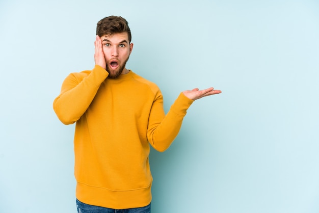 Jonge blanke man op blauw geïmponeerd bedrijf kopie ruimte op palm.