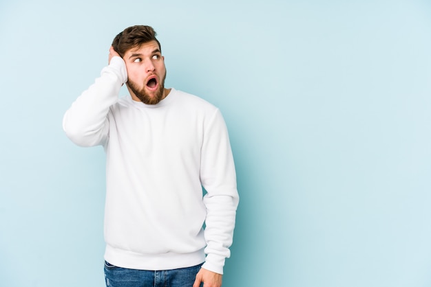 Jonge blanke man op blauwe muur wordt geschokt, ze heeft belangrijke bijeenkomst herinnerd.