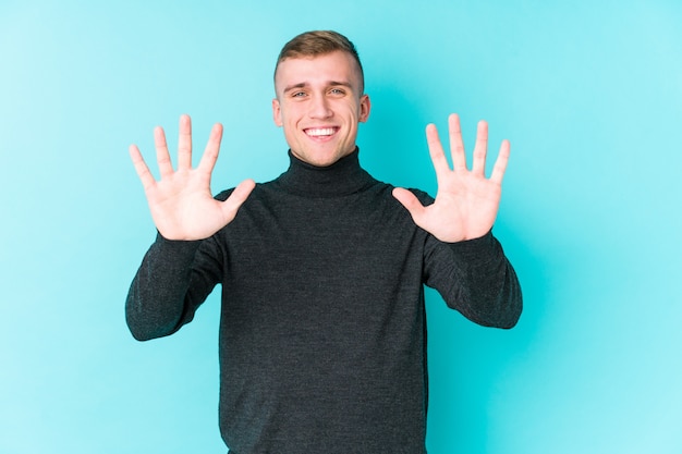 Foto jonge blanke man op een blauwe muur met nummer tien met handen.