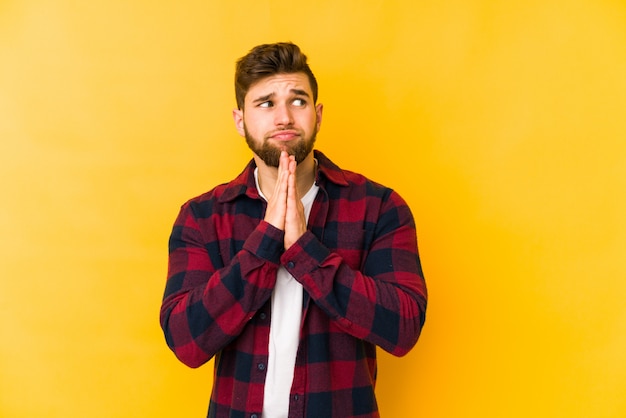 Jonge blanke man op gele muur bidden, tonen toewijding, religieuze persoon op zoek naar goddelijke inspiratie.