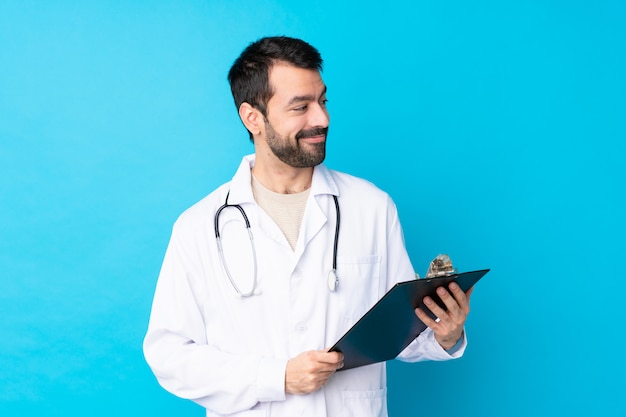 Jonge blanke man over geïsoleerde het dragen van een dokter jurk en met een map