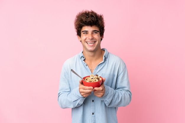 Jonge blanke man over geïsoleerde roze muur met een kom ontbijtgranen