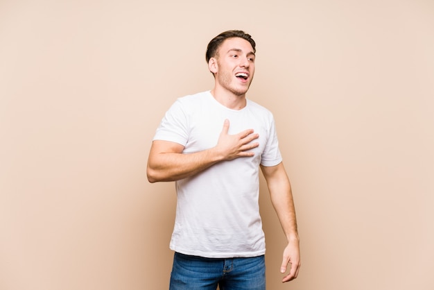 Jonge blanke man poseren geïsoleerd lacht luid houden hand op de borst.